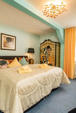 Innenaufnahme Zimmer mit Doppelbett, Kleiderschrank und Sitzecke