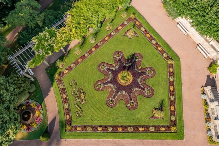 Luftaufnahme bunt bepflanztes Teppichbeet mit Idolino-Brunnen im Schlosspark Altenstein