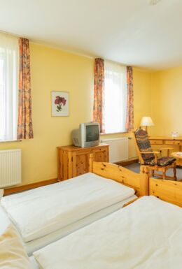 Innenaufnahme Zimmer mit Doppelbett, TV und Sitzbereich