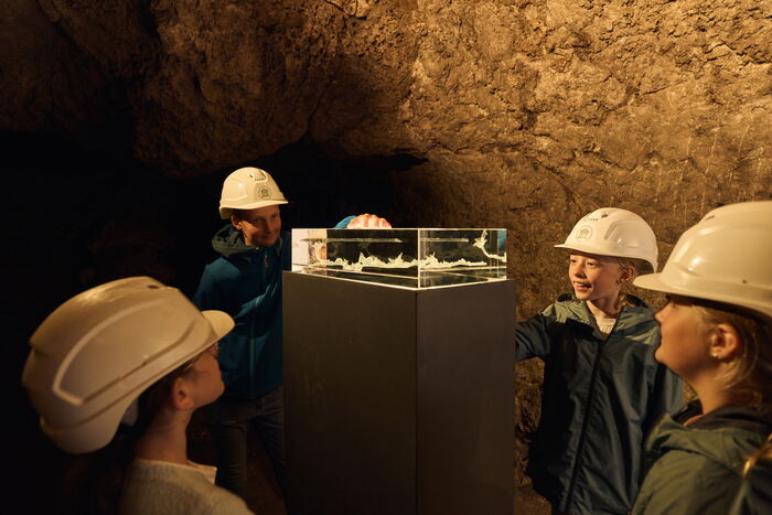 Kinder stehen um ein beleuchtetes 3D-Modell der Altensteiner Höhle aus Glas
